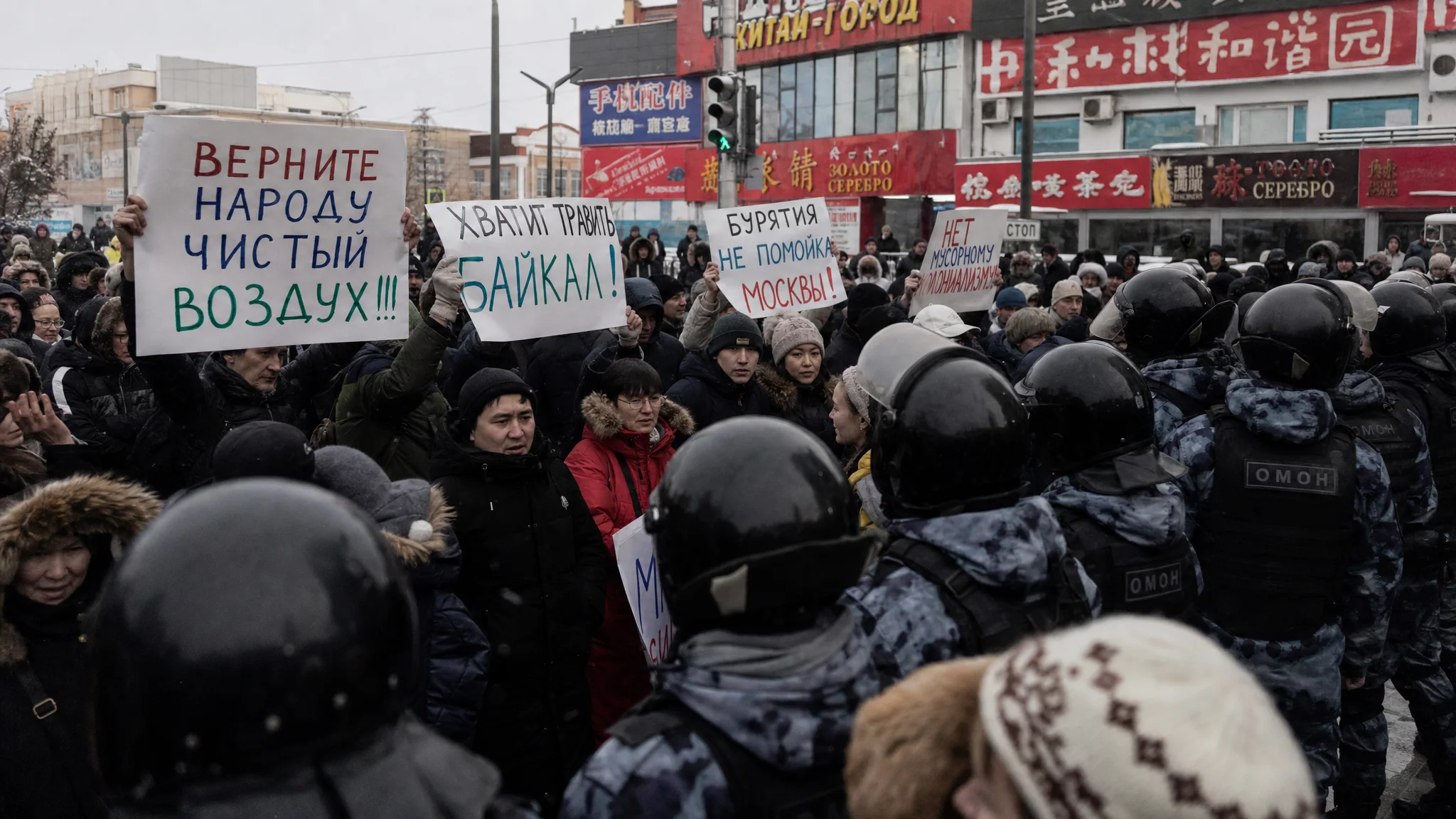 Russian protesters with environmental signs confront armored riot police amid Chinese signage in a Siberian city square. Russian protesters with environmental signs confront armored riot police amid Chinese signage in a Siberian city square.