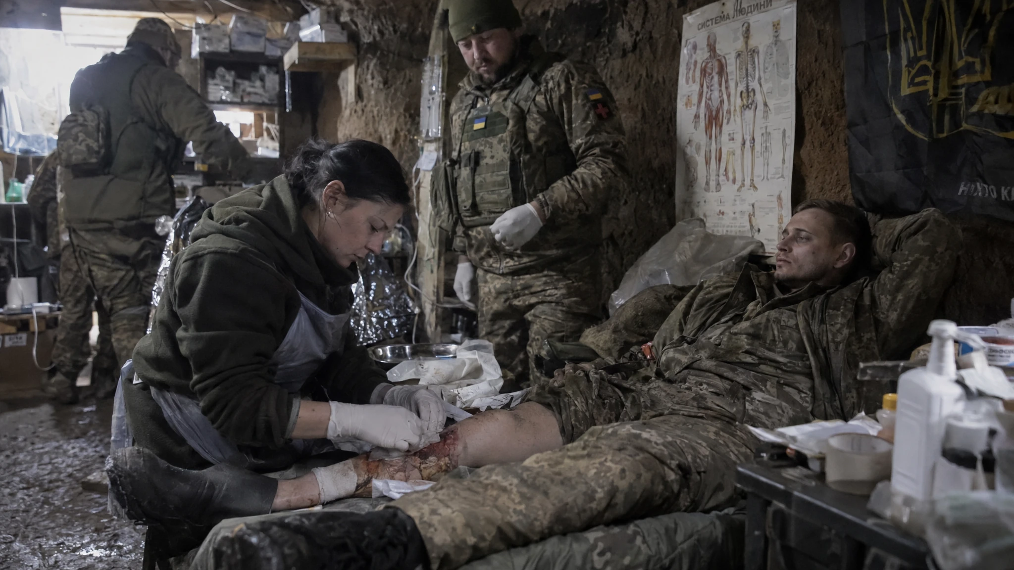 A Ukrainian clinician dresses a Russian prisoner’s leg wound inside a dim field treatment shelter. A Ukrainian clinician dresses a Russian prisoner’s leg wound inside a dim field treatment shelter.