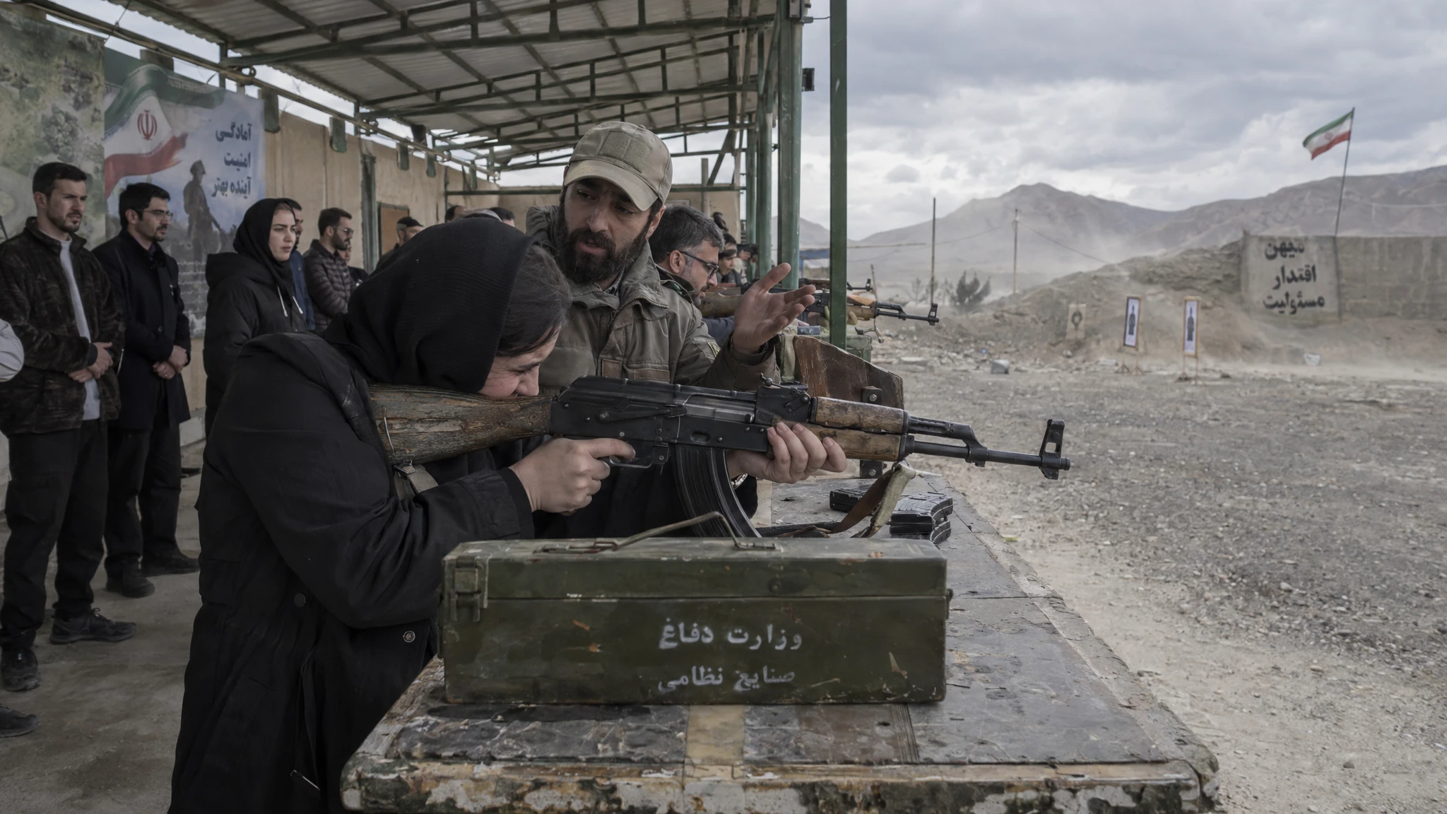 Adults take part in supervised rifle training at an outdoor range in Iran. Adults take part in supervised rifle training at an outdoor range in Iran.
